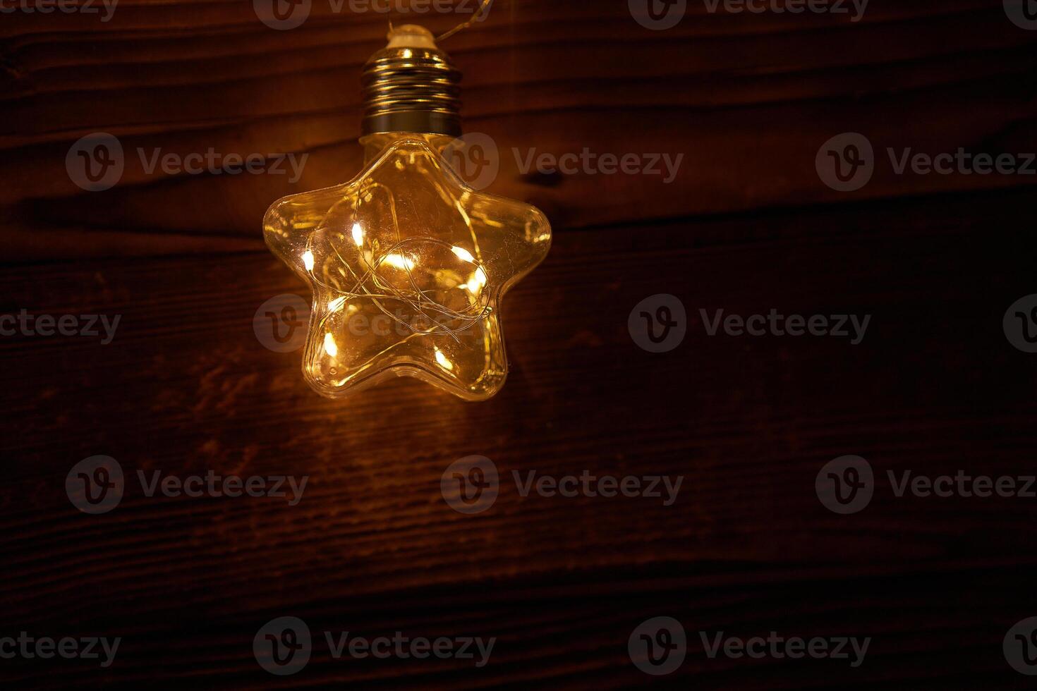 Bright luminous Christmas garlands in the shape of stars lie on a dark wooden background. photo
