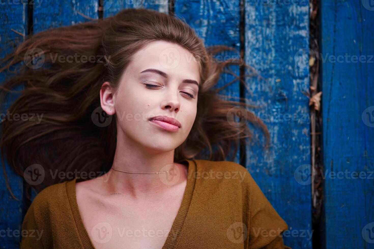 Beautiful caucasian young woman Lying on her back on wooden background. photo