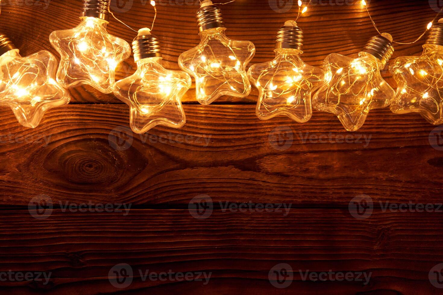 Bright luminous Christmas garlands in the shape of stars lie on a dark wooden background. photo