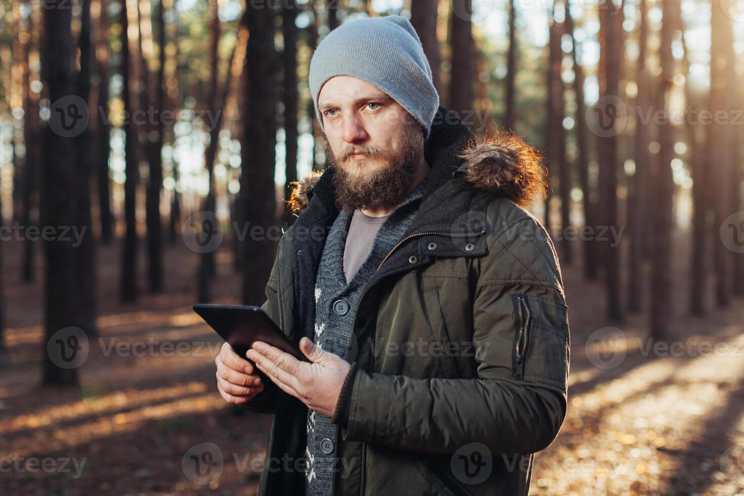 Close up portrait of adult male hiker using digital tab and looking for location during hike in nature. man on hike using digital tablet for navigation. photo