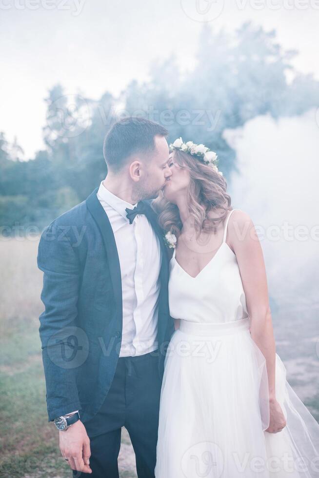 Beautiful bride and groom. Wedding ceremony in nature. Smoke bombs. photo