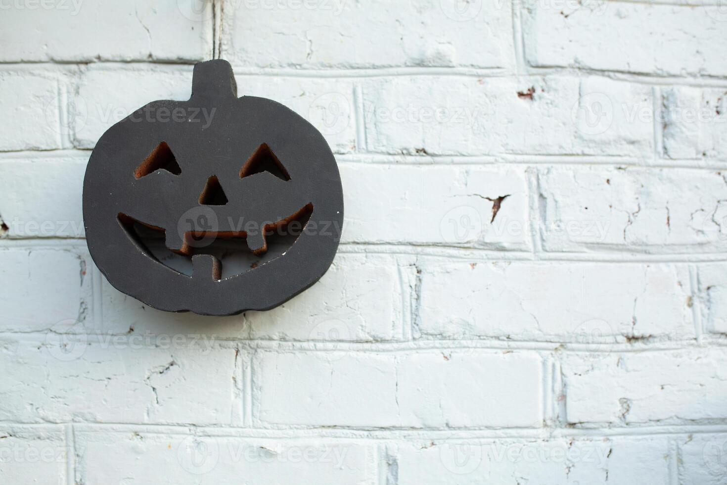 Black halloween pumpkin on the white brick wall background photo