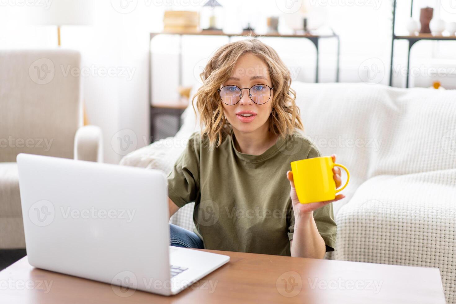 Woman glasses using laptop computer while sitting near sofa with big window on background at home interior photo