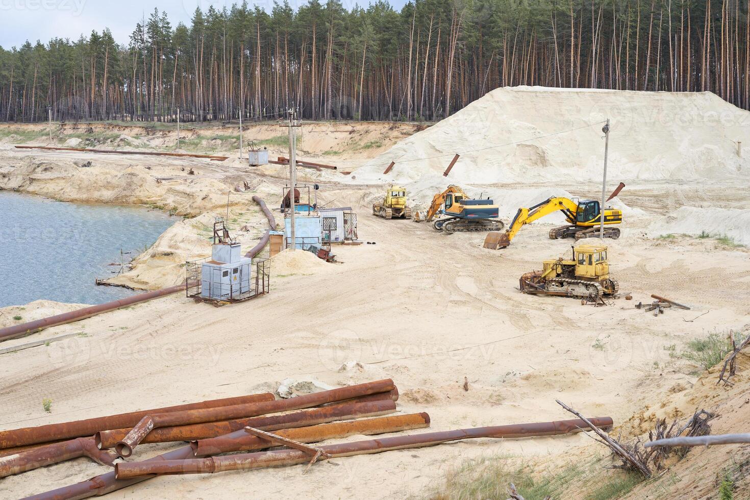 Sand quarry mining industry equipment excavator tractor standing sand land near lake water photo