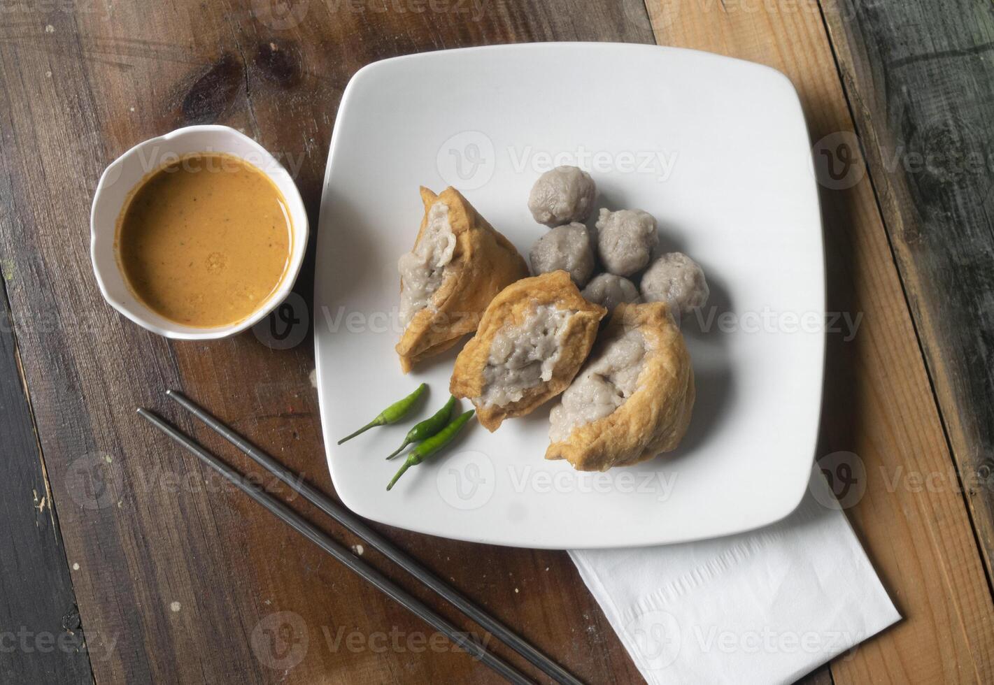 top view tofu and meatball on white disk with peanut sauce photo
