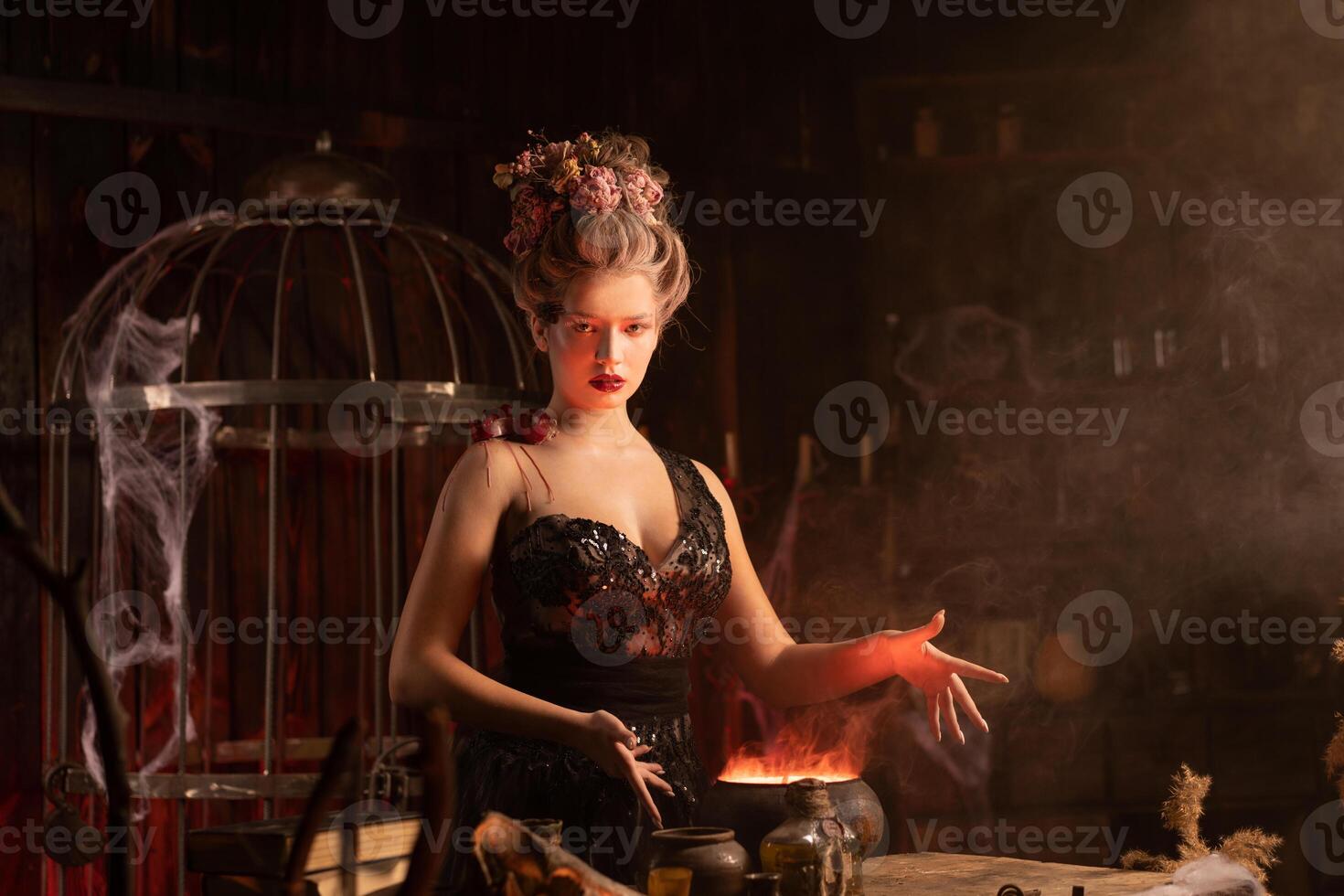 Halloween Witch with cauldron. Beautiful young woman conjuring, making witchcraft photo