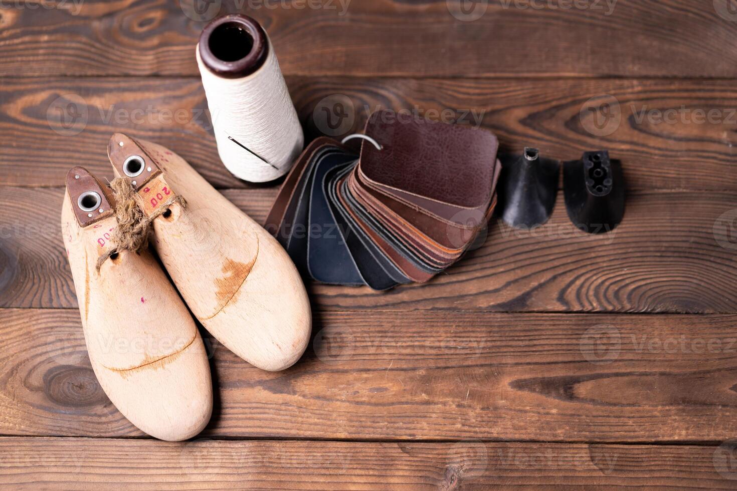 Leather samples for shoes and wooden shoe last on dark wooden table. photo