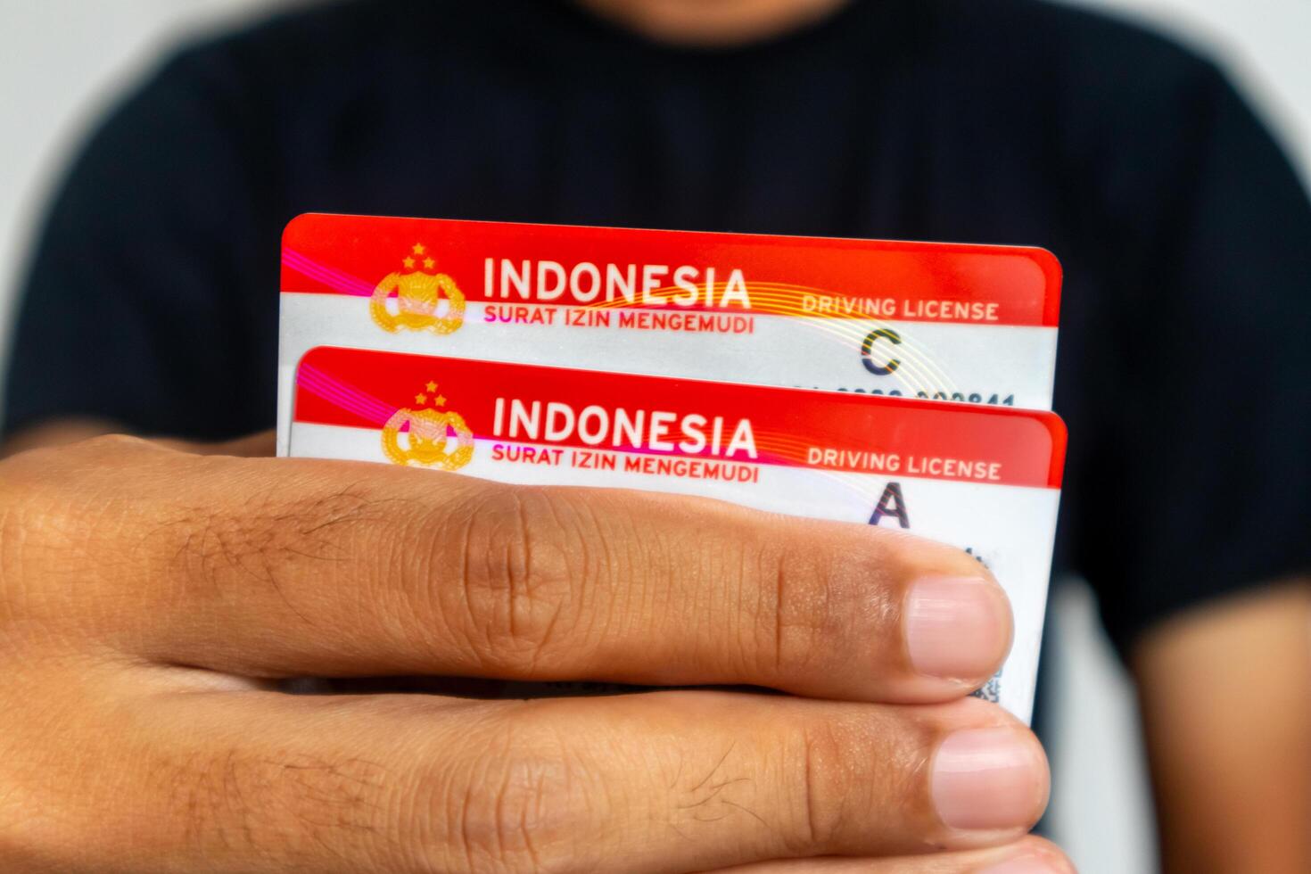 Jakarta, Indonesia, 2024 - A man in black clothes holding the Indonesia driving license for car and motorcycle photo