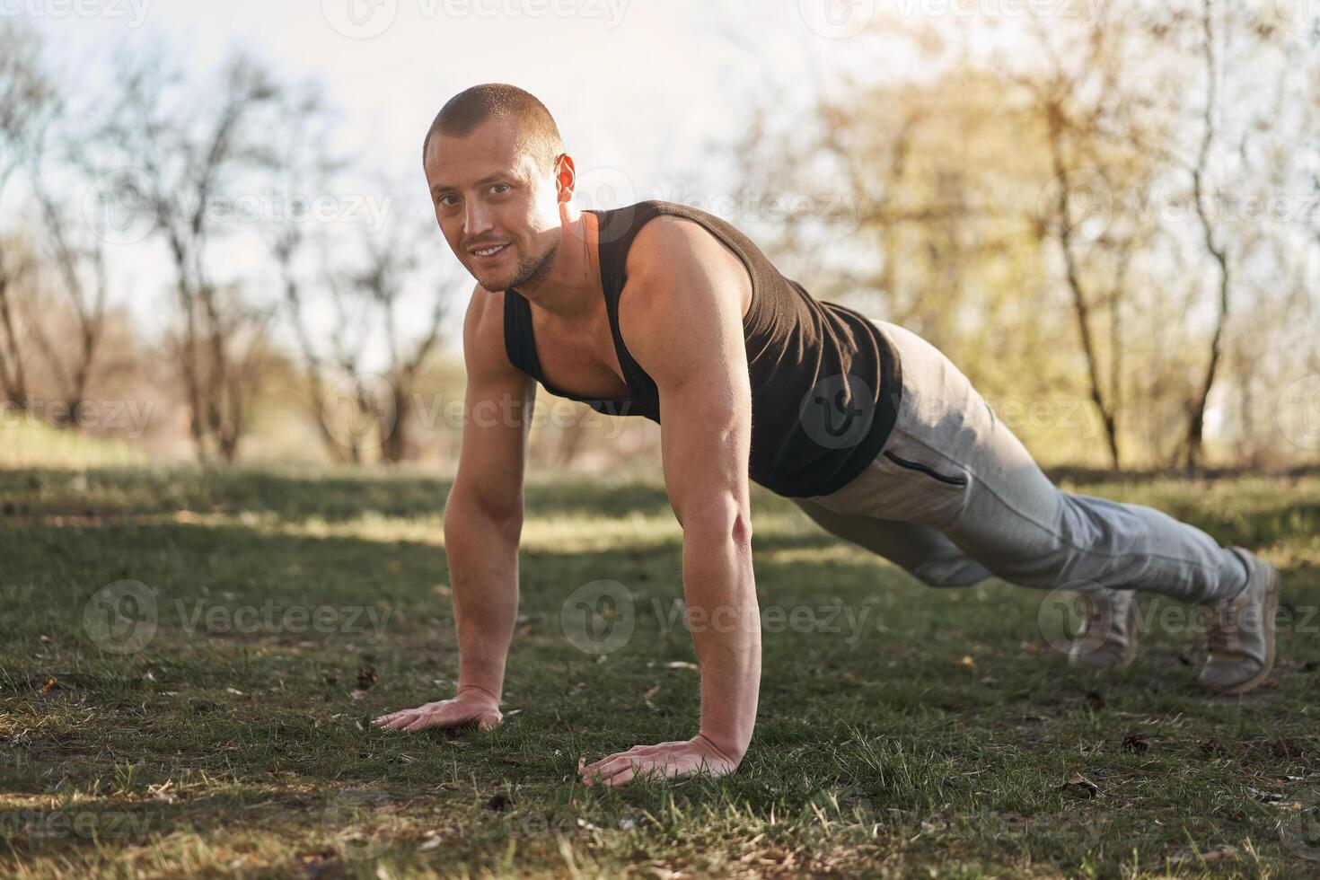 Strong men outdoor plank workout exercise. Young adult caucasian man do morning workout nature forest photo