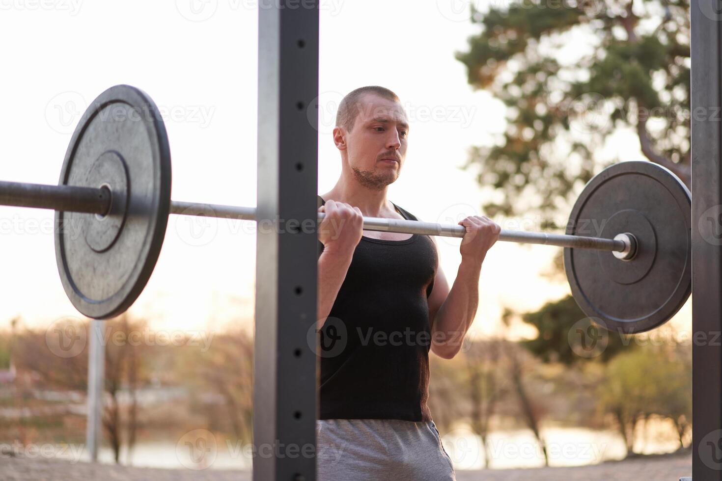 Man with barbell outdoor gym on nature in park. photo