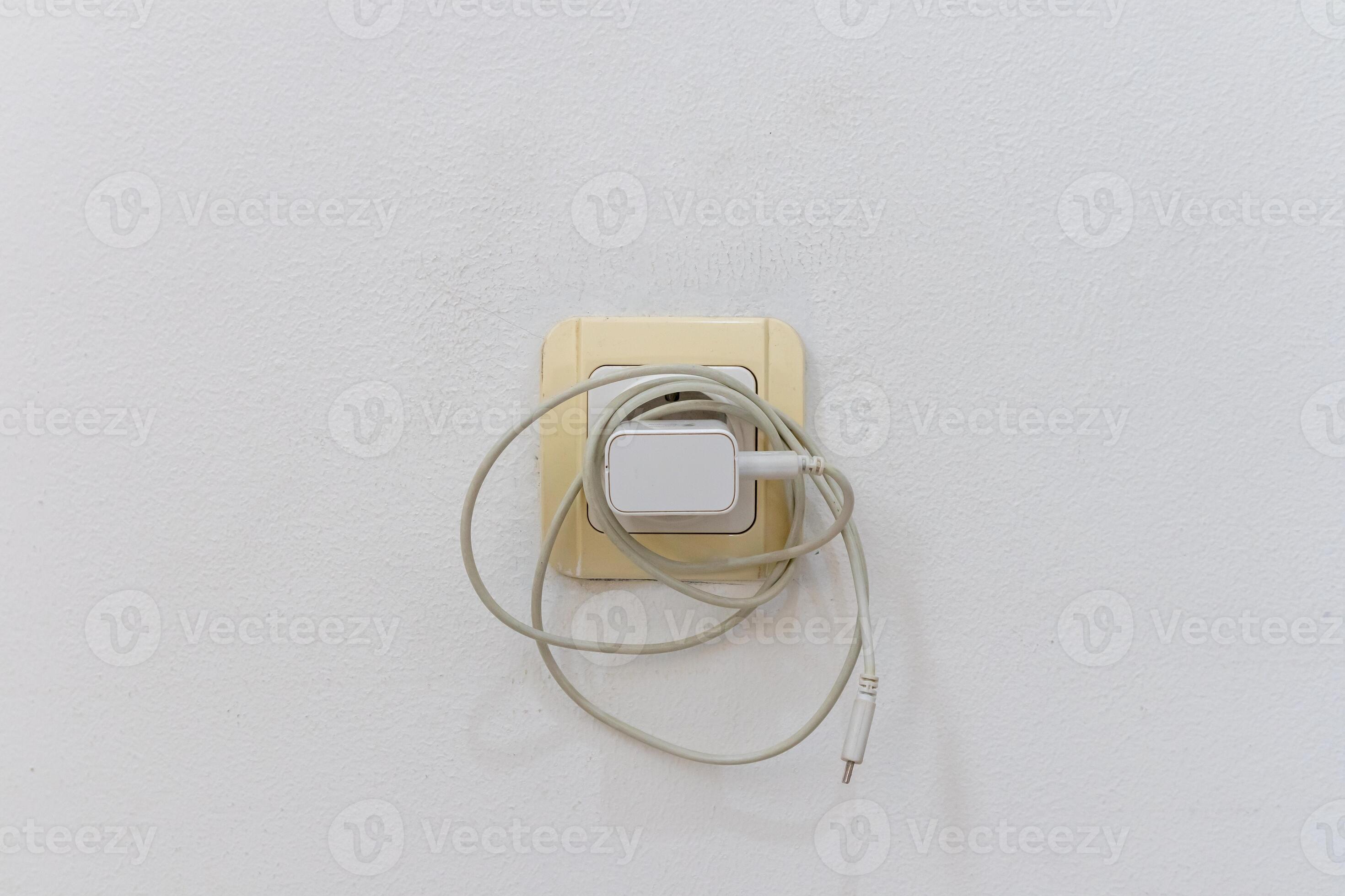 The phone charger is plugged into the electrical power socket on wall when not in use. Leaving