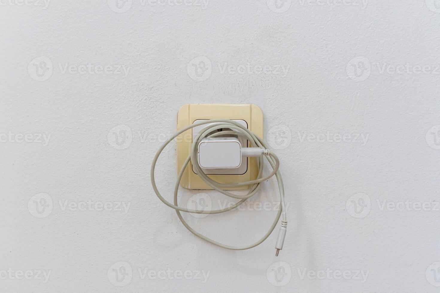 el teléfono cargador es atascado dentro el eléctrico poder enchufe en pared cuando no en usar. dejando el teléfono cargador atascado en. debilitante energía. foto