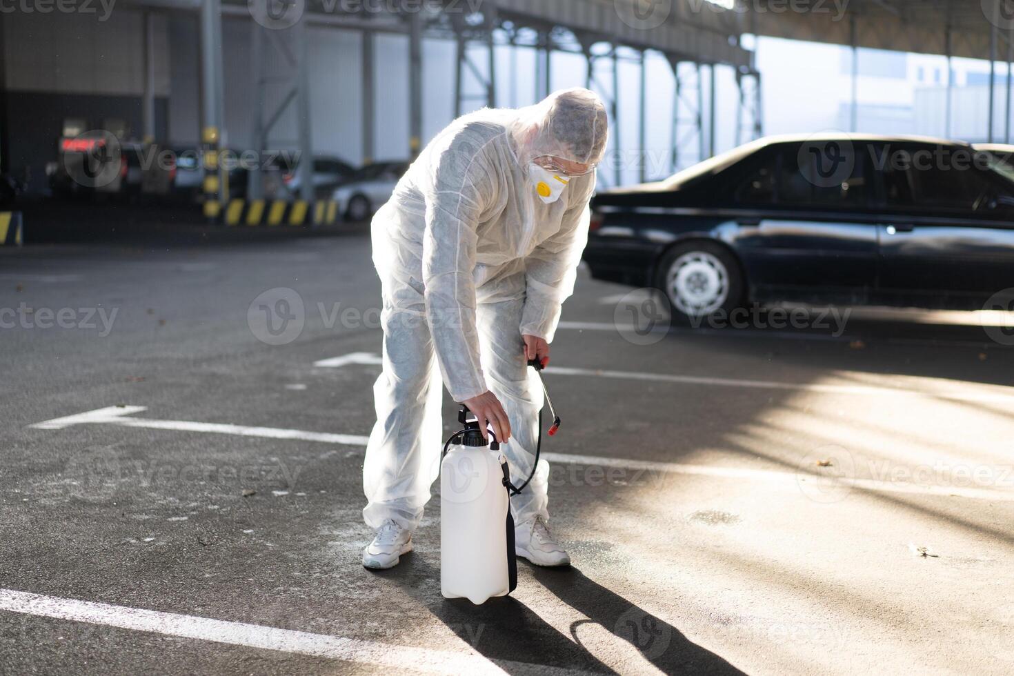 Man dressed white protective overalls spraying surface antibacterial sanitizer sprayer during quarantine photo