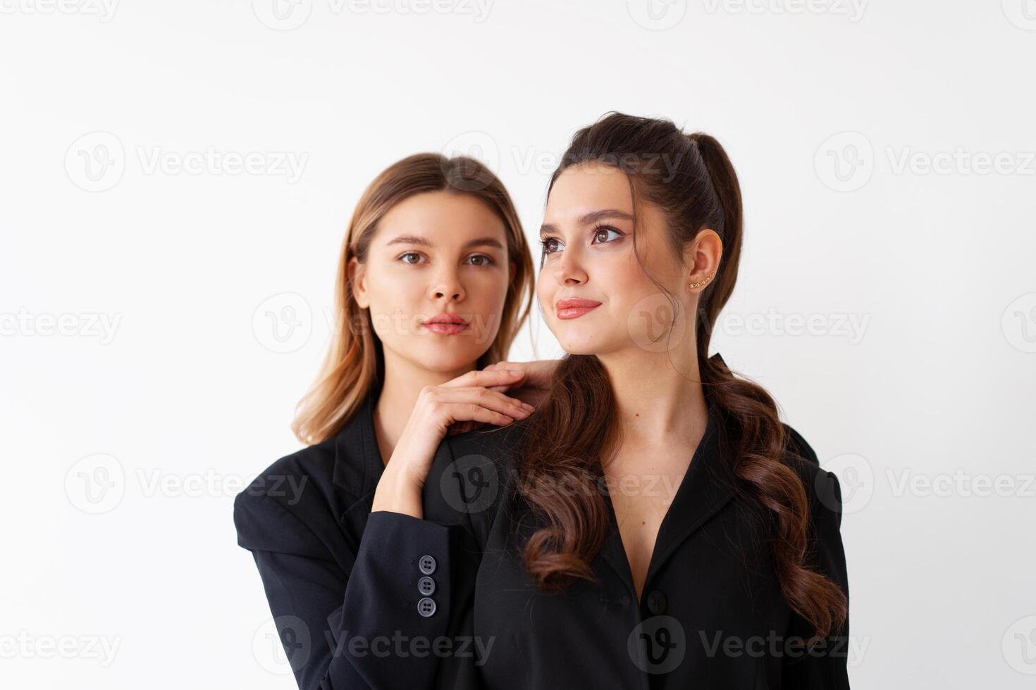 Concept of partnership in business. Two Young businesswoman dressed black formal suit standing studio isolated white background. photo