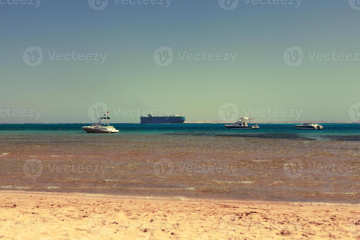 three boats and a tanker in the sea bay with clear water photo