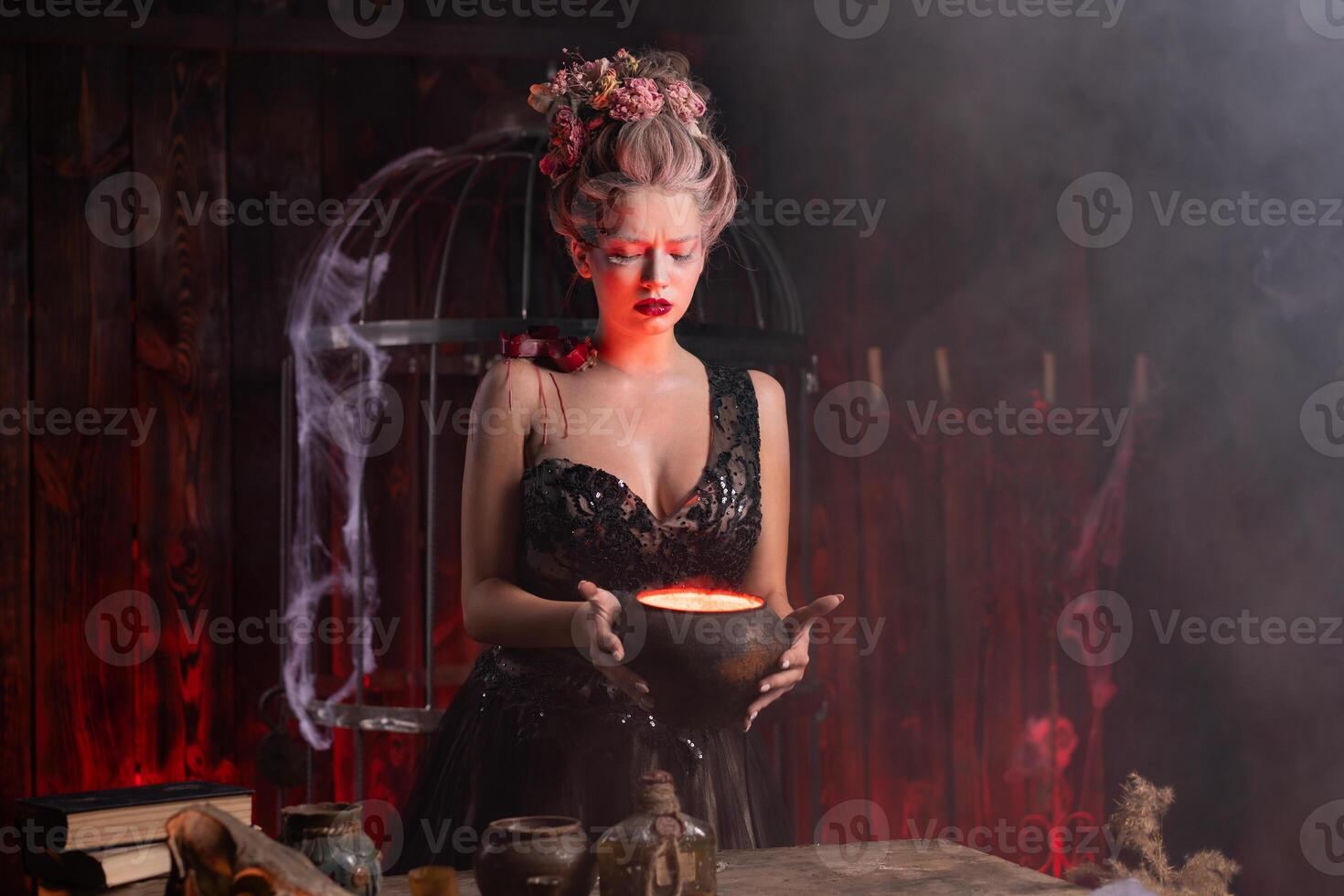 Halloween Witch with cauldron. Beautiful young woman conjuring, making witchcraft photo