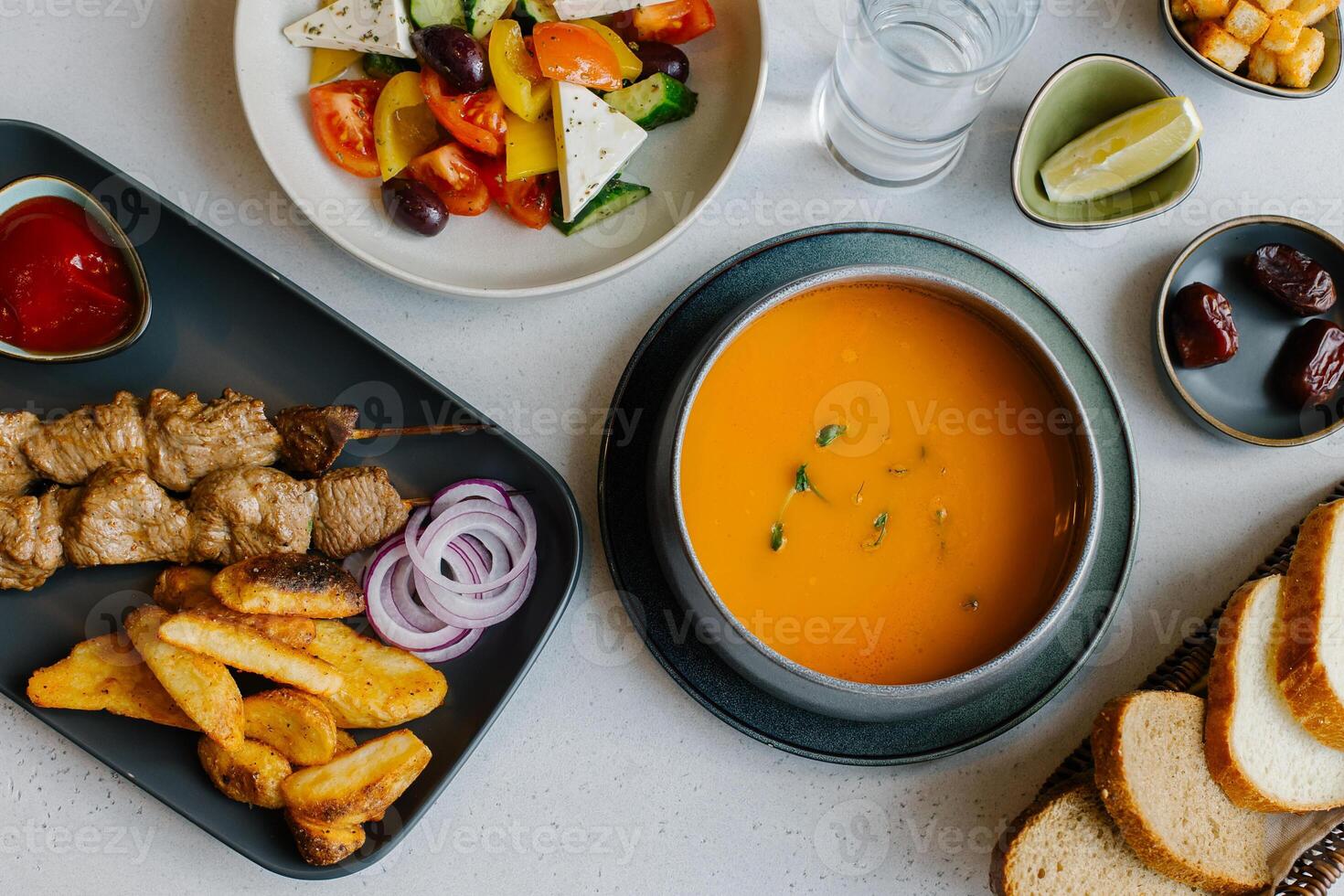 Lentil soup, beef skewers with baked potatoes and Greek salad. Glass of water and bowl of dates. Ramadan food preparation for iftar meal photo