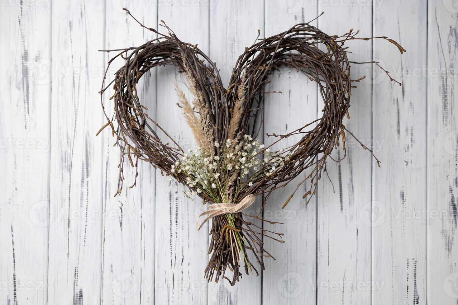 Wicker heart shaped wreath of birch branches hanging on aged wooden wall photo