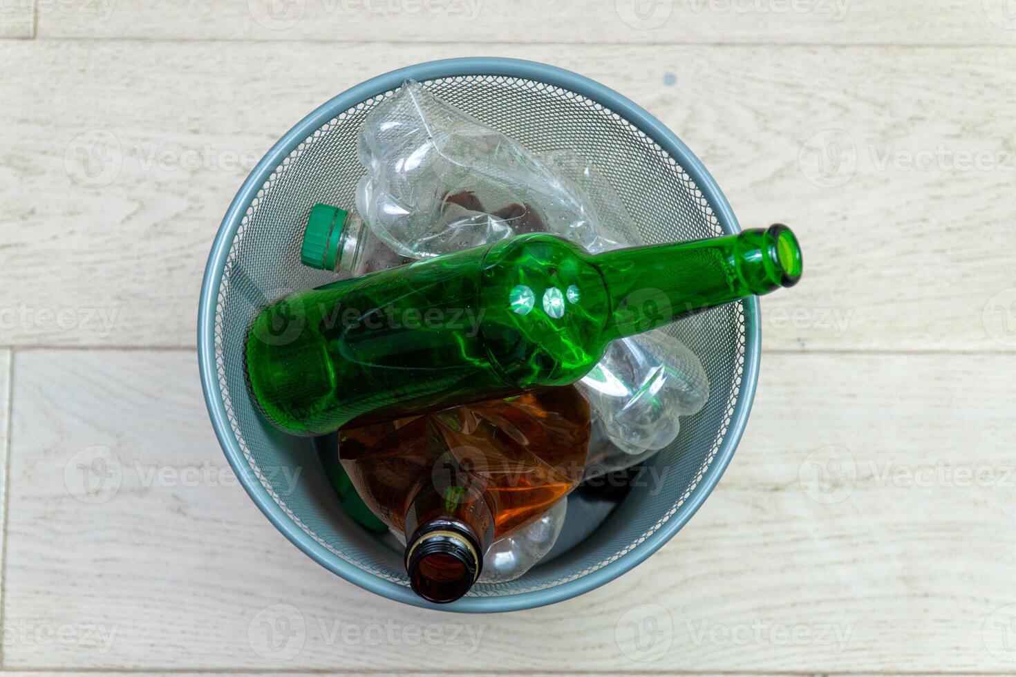 Different plastic and glass bottles in the office trash can. Ecology and recycling of waste from various raw materials photo