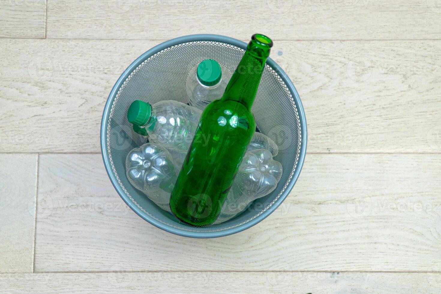 Six different plastic and glass bottles in the office trash can. Ecology and recycling of waste from various raw materials photo