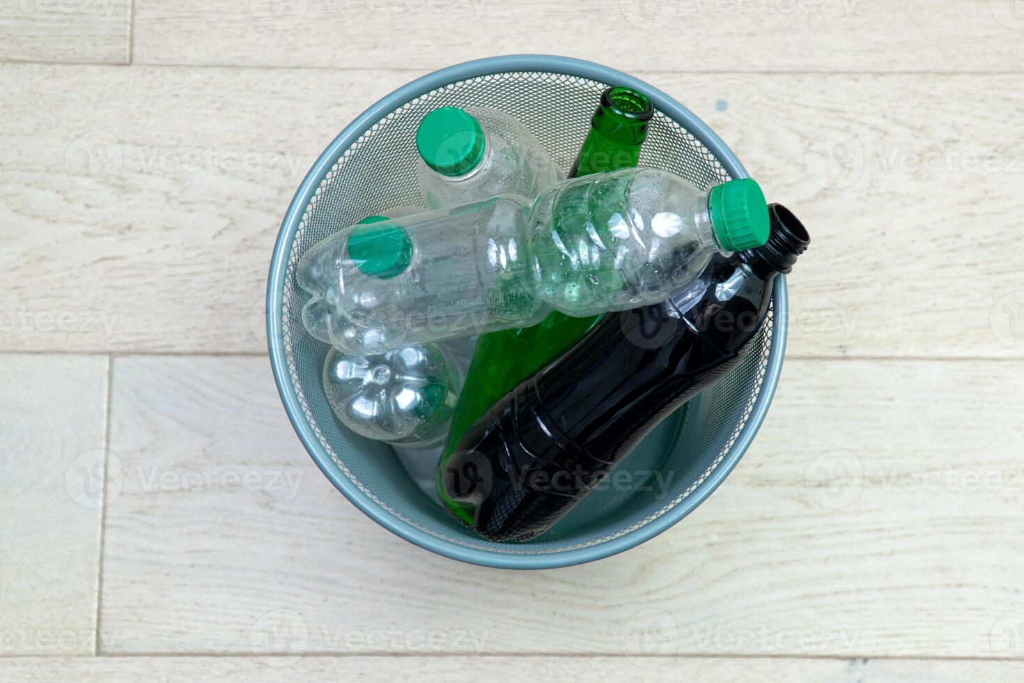 Six different plastic and glass bottles in the office trash can. Ecology and recycling of waste from various raw materials photo