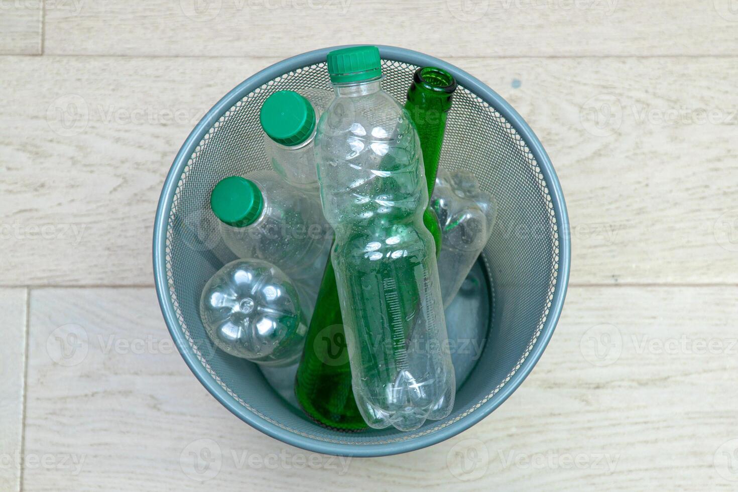 Six different plastic and glass bottles in the office trash can. Ecology and recycling of waste from various raw materials photo