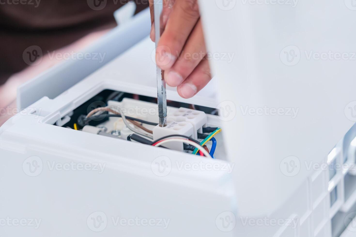 Technician man using a screwdriver to fix and install new air conditioner, repair service, and install new air conditioning concepts photo