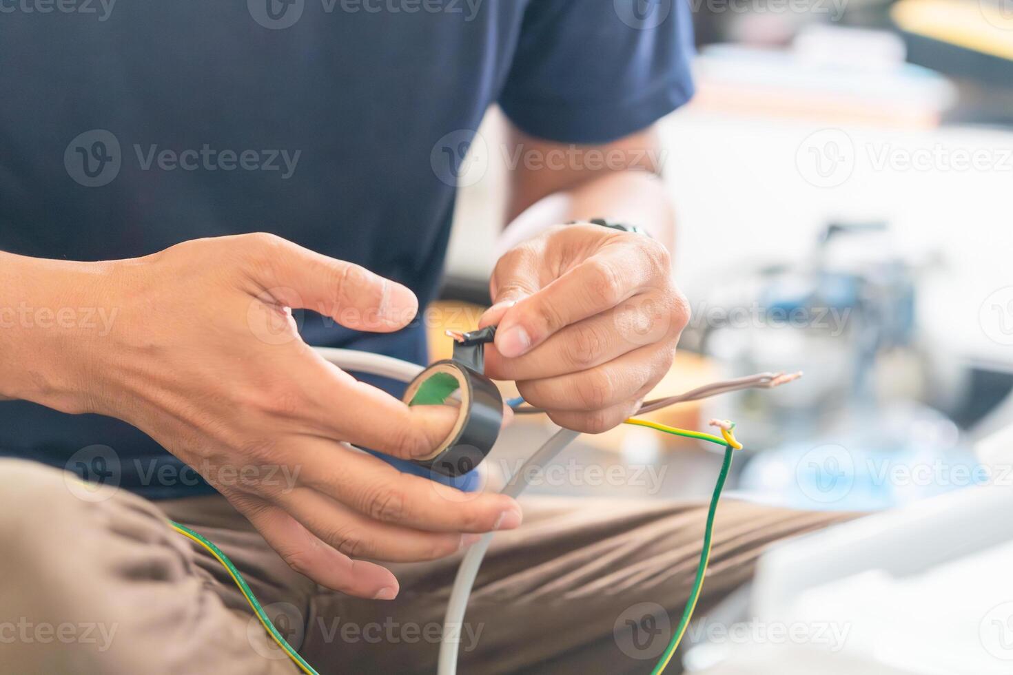 Technician man winds electrical tape around the wires to install new air conditioning, repairing servicing, and install new air conditioner concepts photo