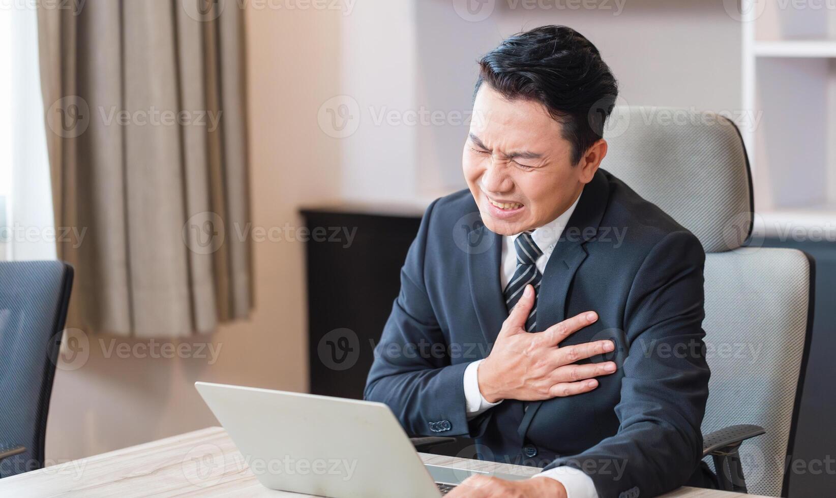 Unhappy man presses a hand to chest has heart attack suffers from unbearable pain, Businessman with pain on heart in meeting room photo