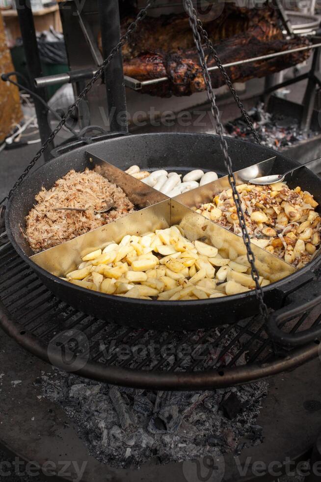 Roasted potatoes cooked outdoors in big metal cauldron pot. Street fast food photo