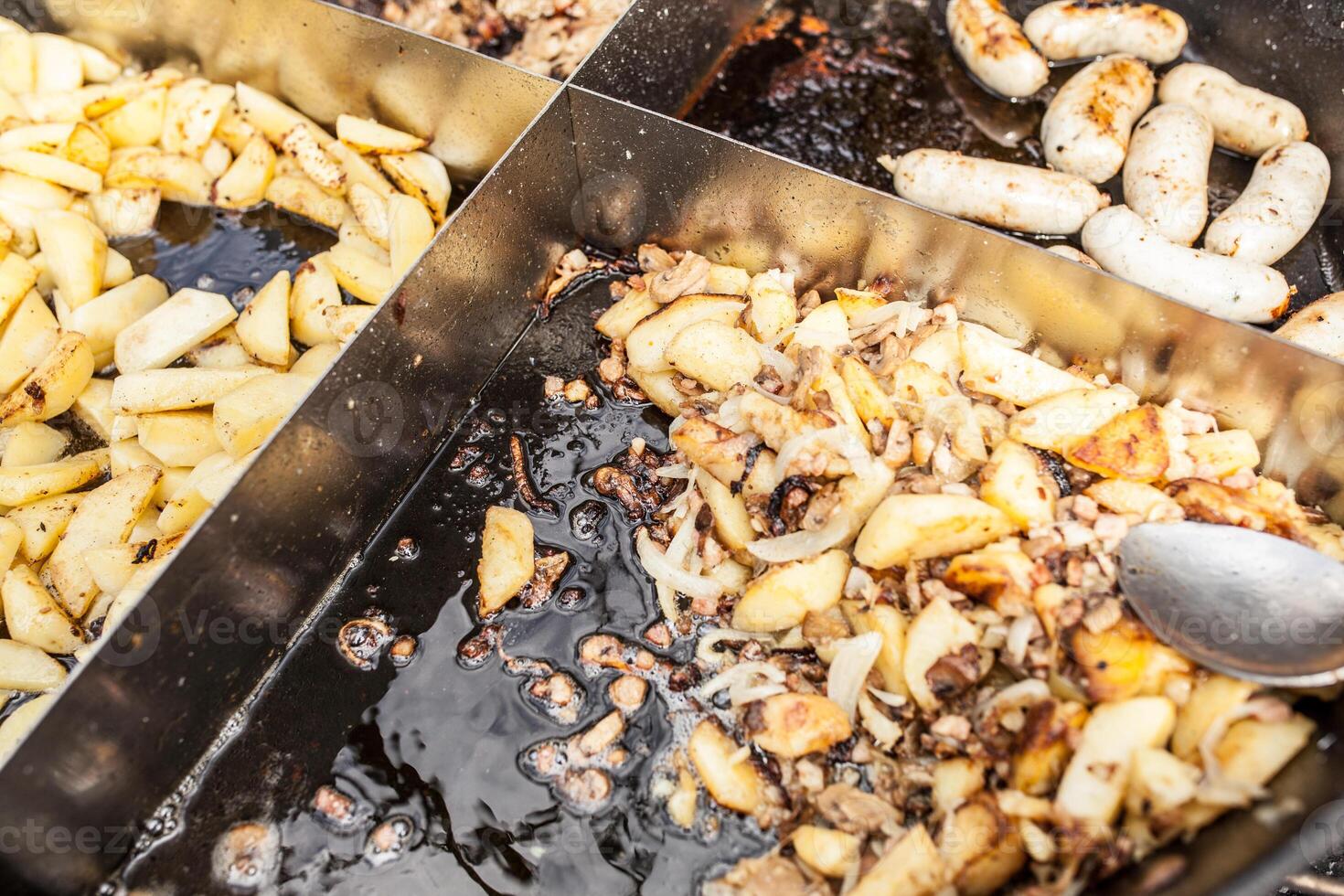 Roasted potatoes cooked outdoors in big metal cauldron pot. Street fast food photo