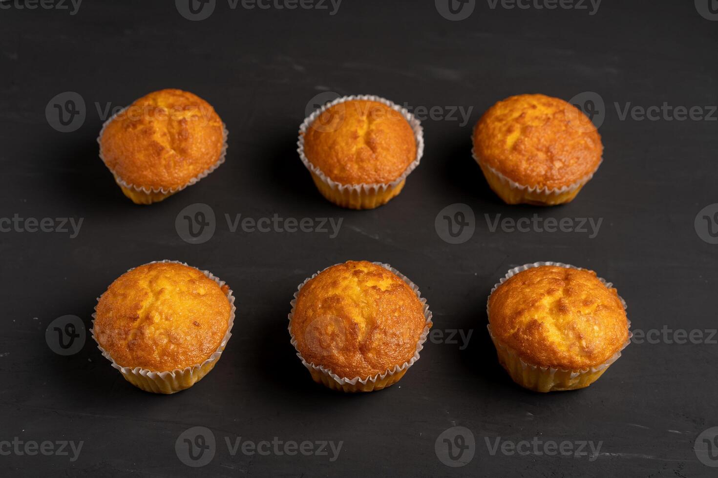 Appetizing muffins stand on a table top view. Traditional pastries on a dark background minimalism. photo