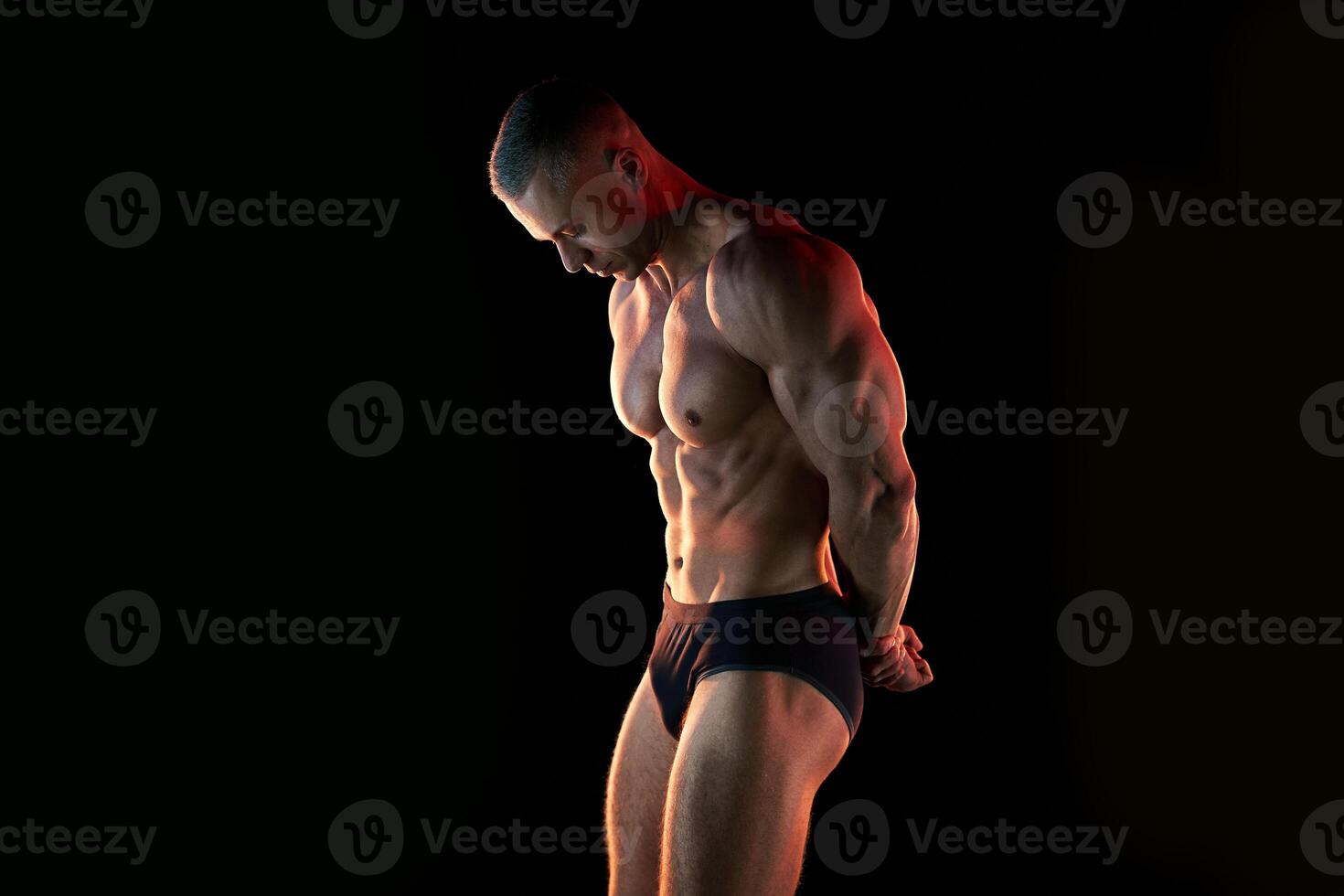 Active lifestyle concept. Professional bodybuilder showing perfect muscular body, lamps illumination on background photo