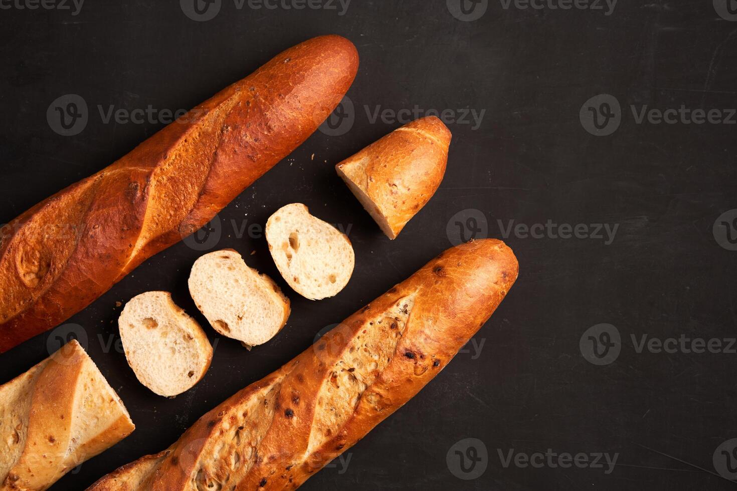 Three crispy french baguettes lie on an old wooden table with free space for text photo