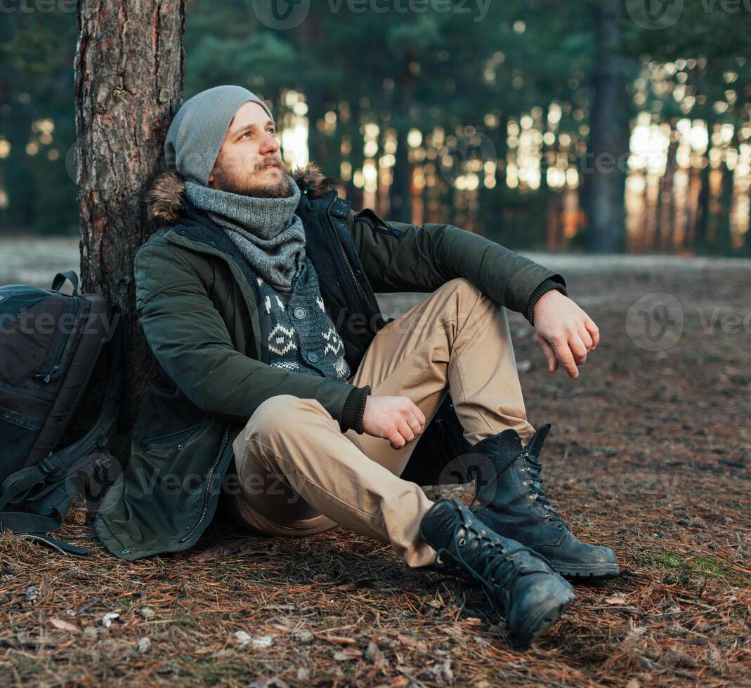 Pensive hipster guy wanderlust with touristic backpack enjoy tranquility during exploring nature environment, male hiker thinking about route to discover photo