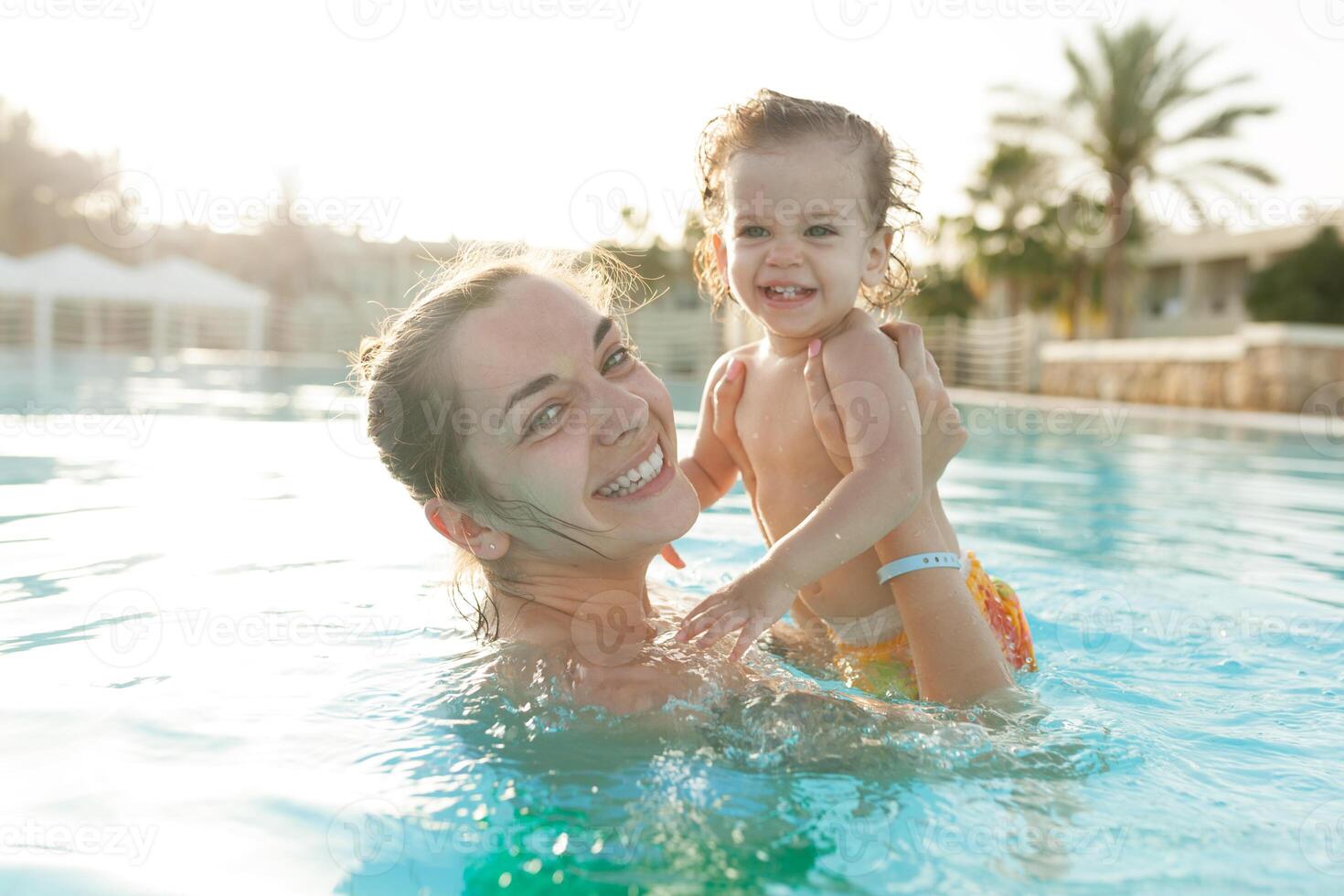 Mom and little daughter are played in the open swimming pool. Family with one child on vacation in warm countries. Positive people on vacation. photo