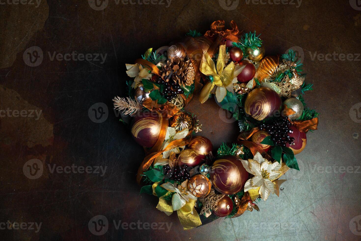 Christmas wreath on brown background with copyspace. Wreath decorated with balls and bows of gold and brown, with green leaves photo