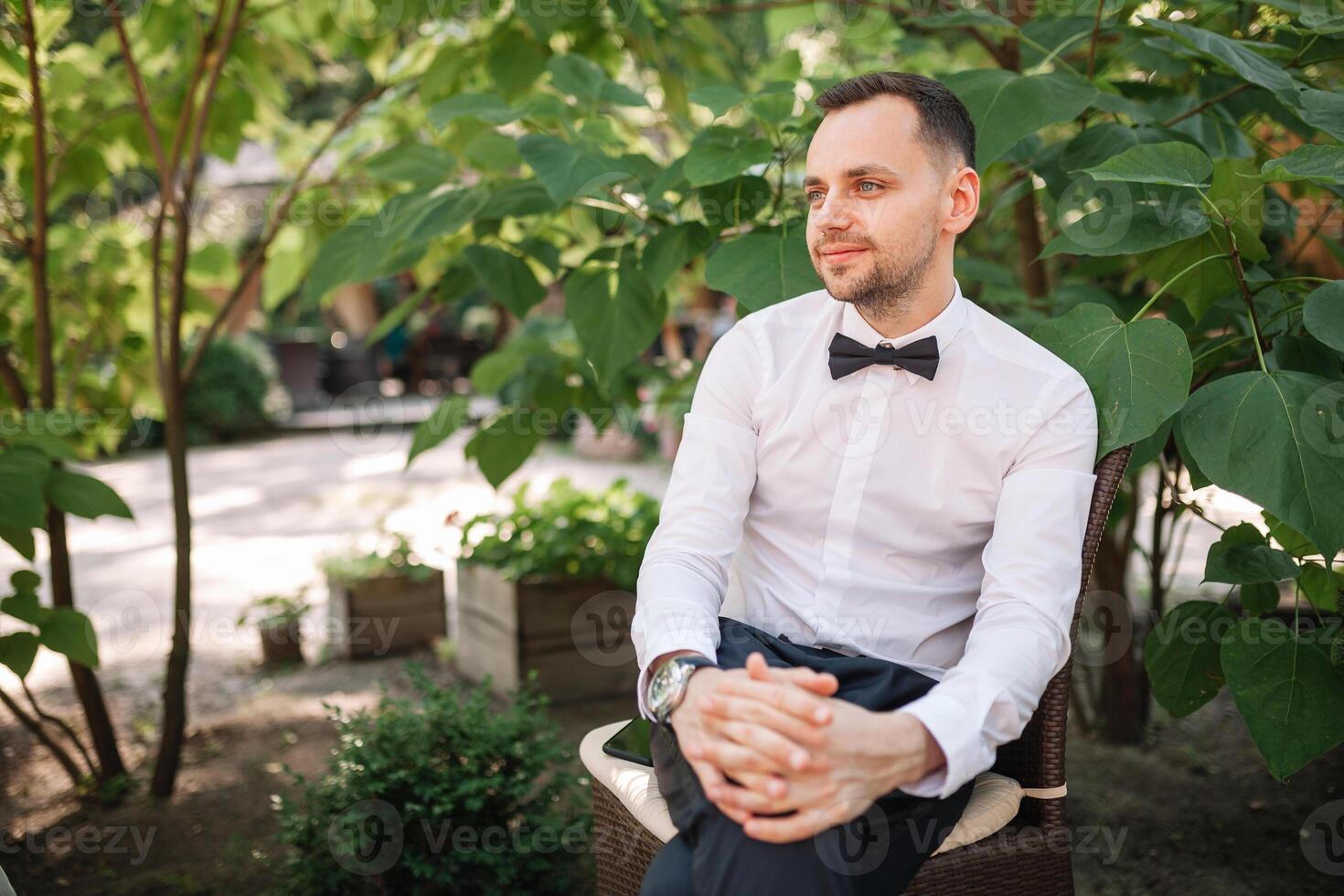 un hermoso joven negocio hombre en un blanco camisa y Corbata un mariposa a un negocio cena murga para su colegas solo a un verano restaurante mesa foto