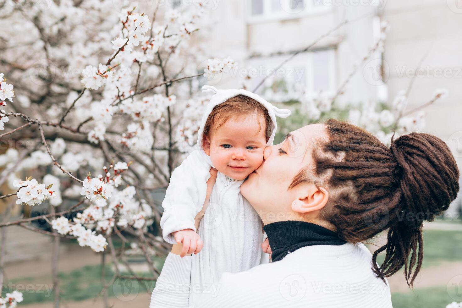 joven madre con adorable hija en parque con florecer árbol. contento madre y niño foto