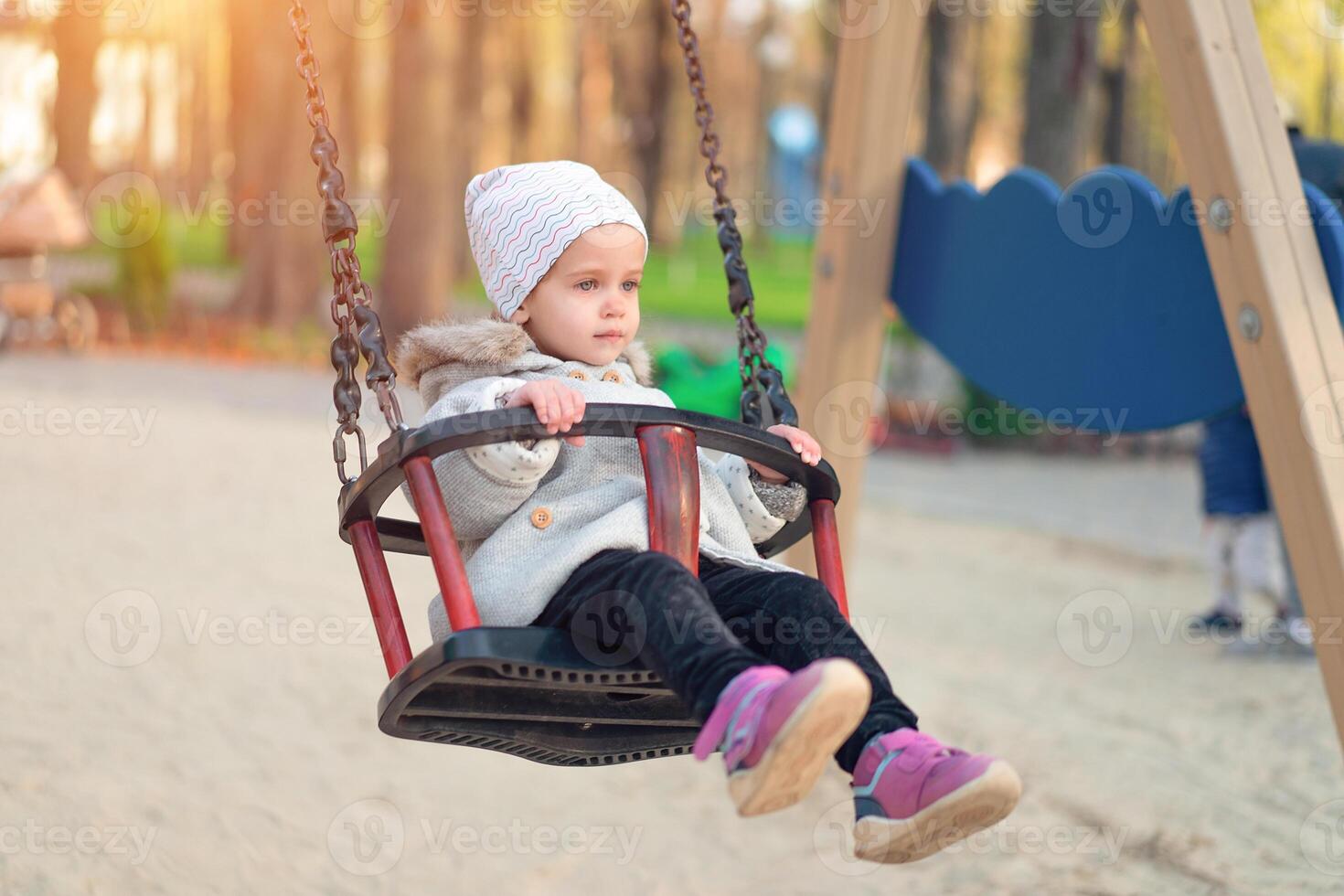 contento niño niña en columpio en puesta de sol caer. pequeño niño jugando en el otoño en el naturaleza parque foto