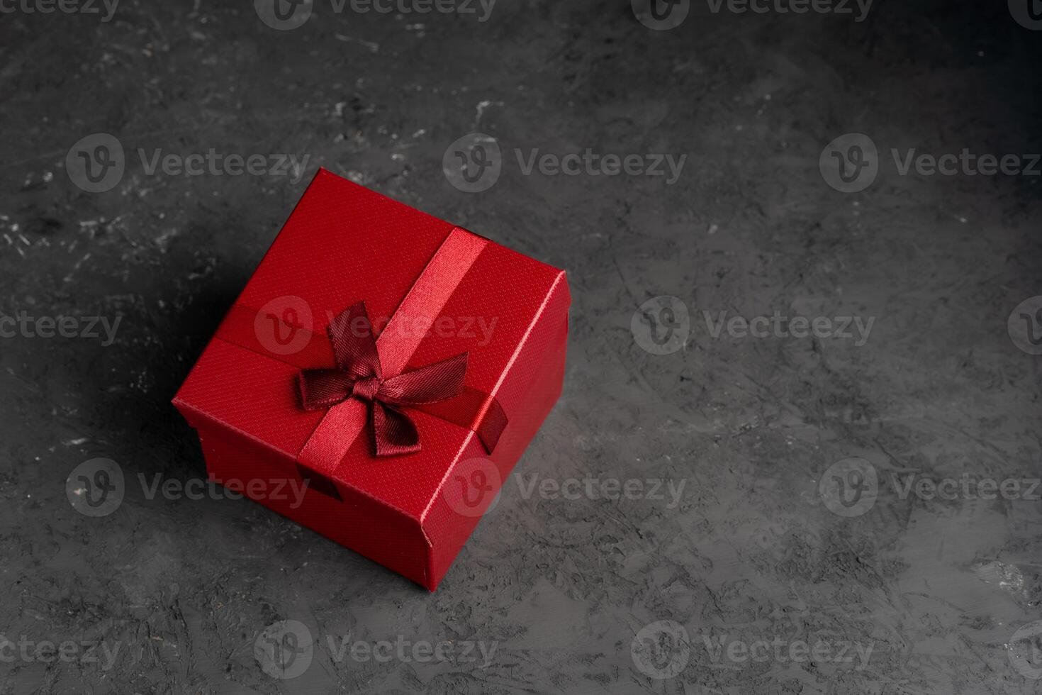 Red square holiday gift box against a dark background photo