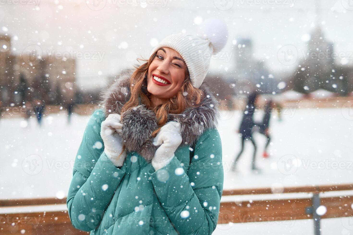 Beautiful lovely middle-aged girl with curly hair warm winter jackets stands ice rink background Town Square. photo