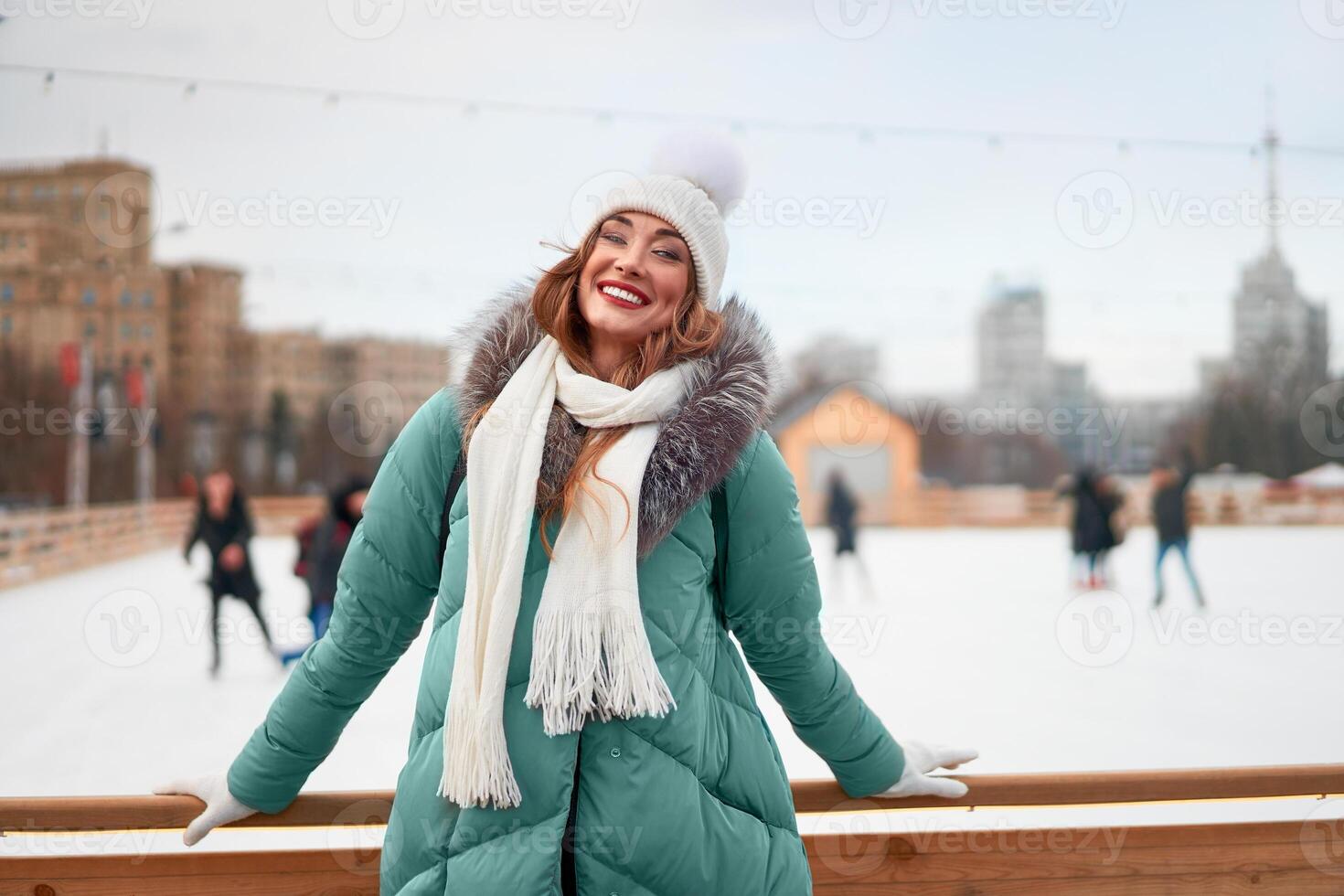 Beautiful lovely middle-aged girl with curly hair warm winter jackets stands ice rink background Town Square. photo