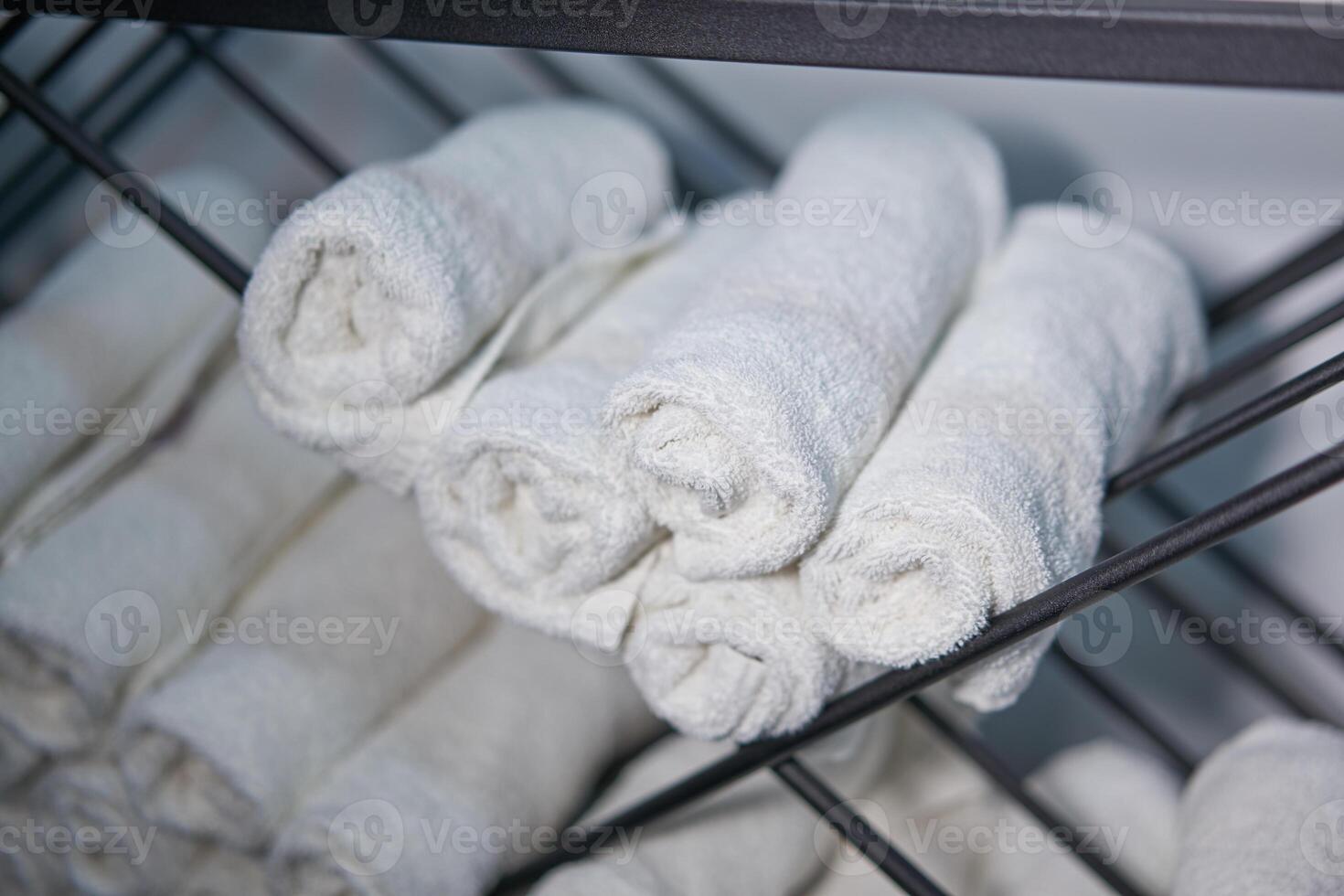 White clean towels rolled up on a roll are stored on shelves in a beauty salon in a barbershop spa. photo