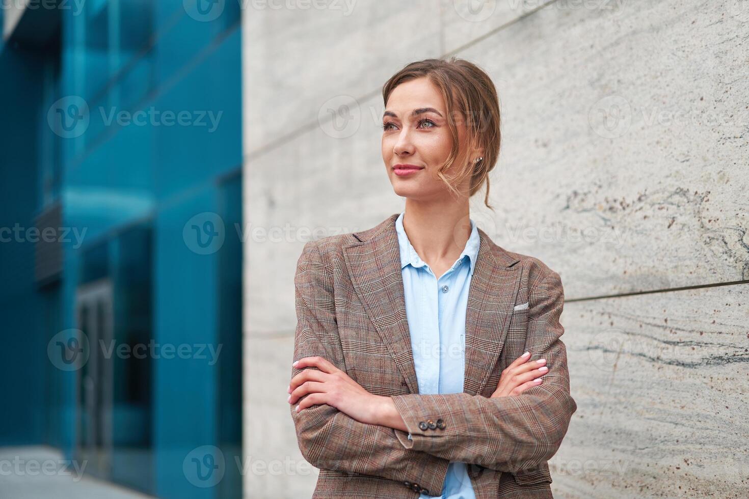 Blonde business woman put her hands together and look away. The hair is gathered in a bun. Business concept. photo