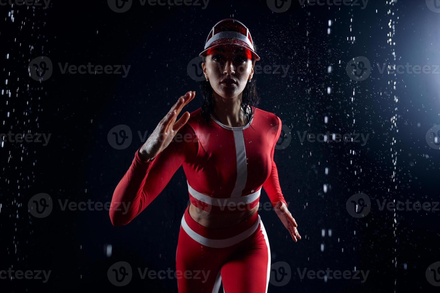 hermosa joven niña en ropa de deporte corriendo en agua estudio. gotas de agua untado acerca de su aptitud cuerpo. el Perfecto figura en el antecedentes de agua salpicaduras malo clima para deporte foto