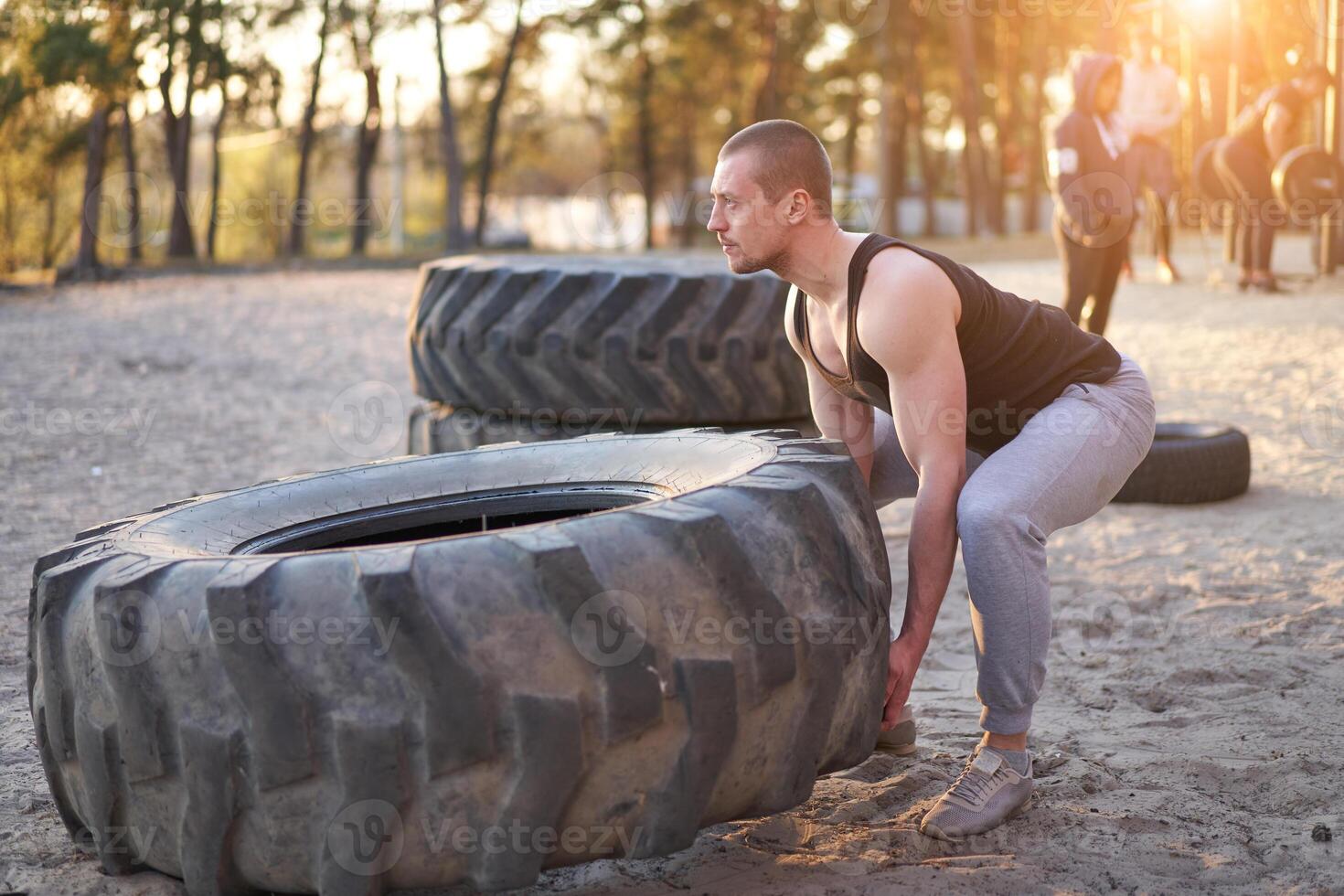 Strong man training workout lifting large tire outdoor DIY gym. photo