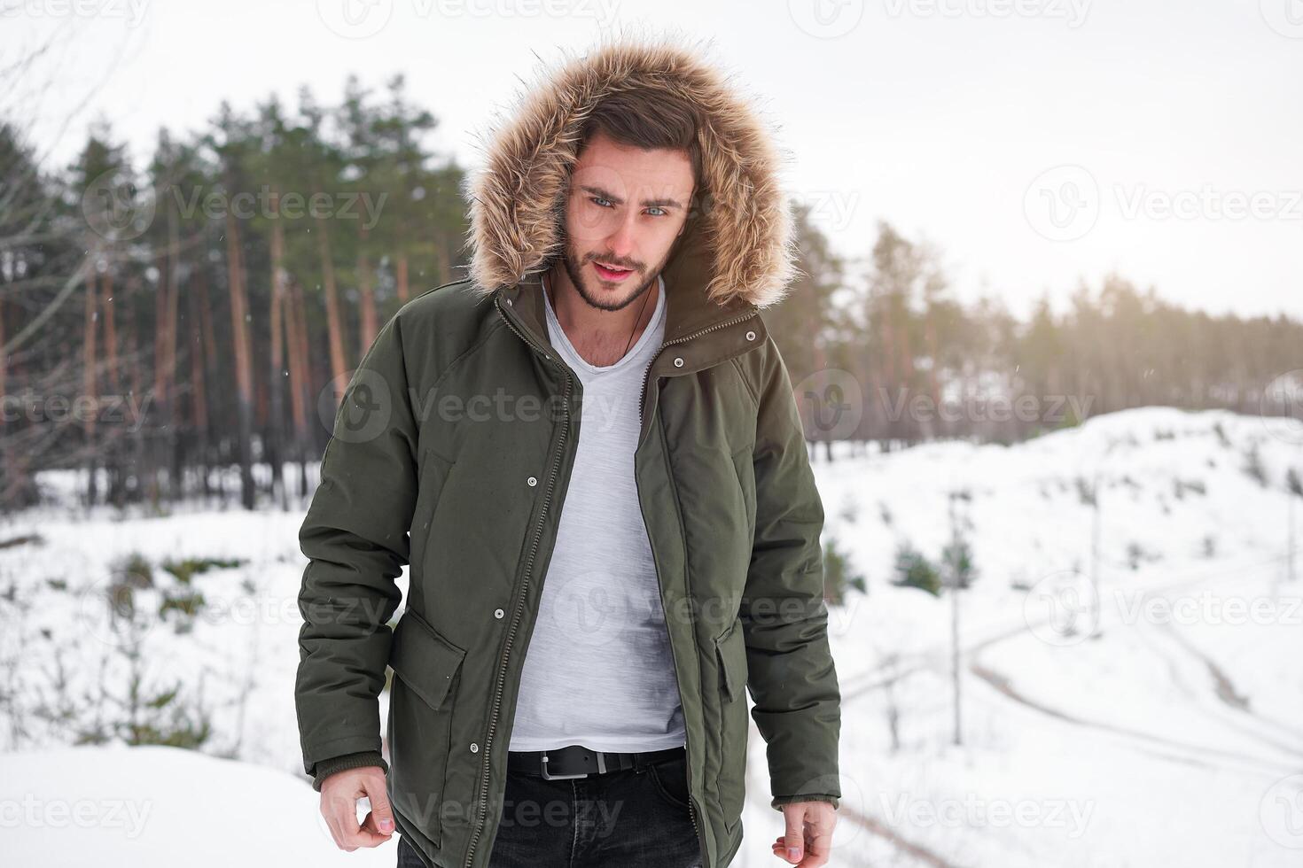 Attractive bearded man standing outdoors in winter season forest. photo