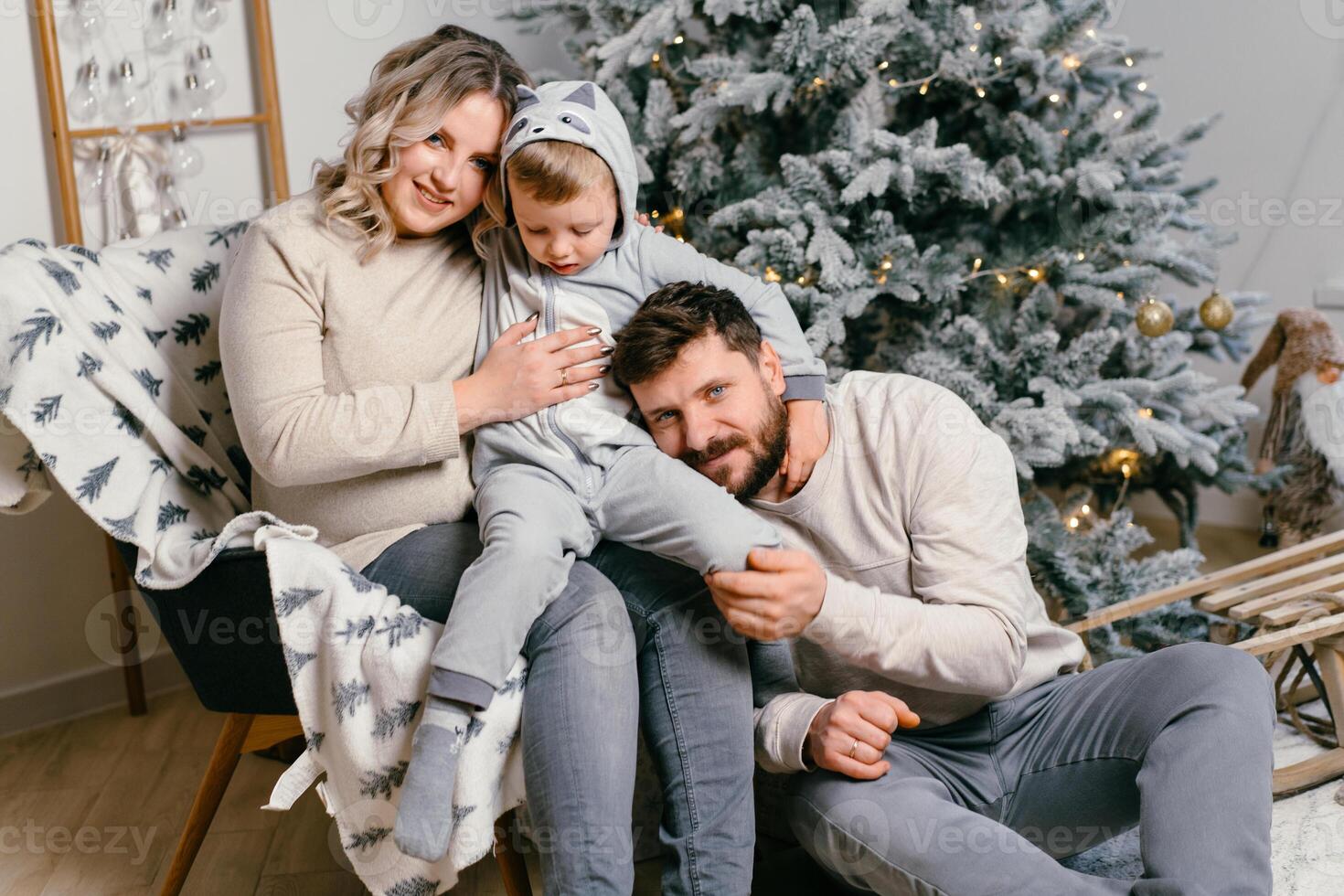 Navidad familia felicidad retrato de papá, embarazada mamá y pequeño hijo sentado Sillón a hogar cerca Navidad árbol abrazo sonrisa foto