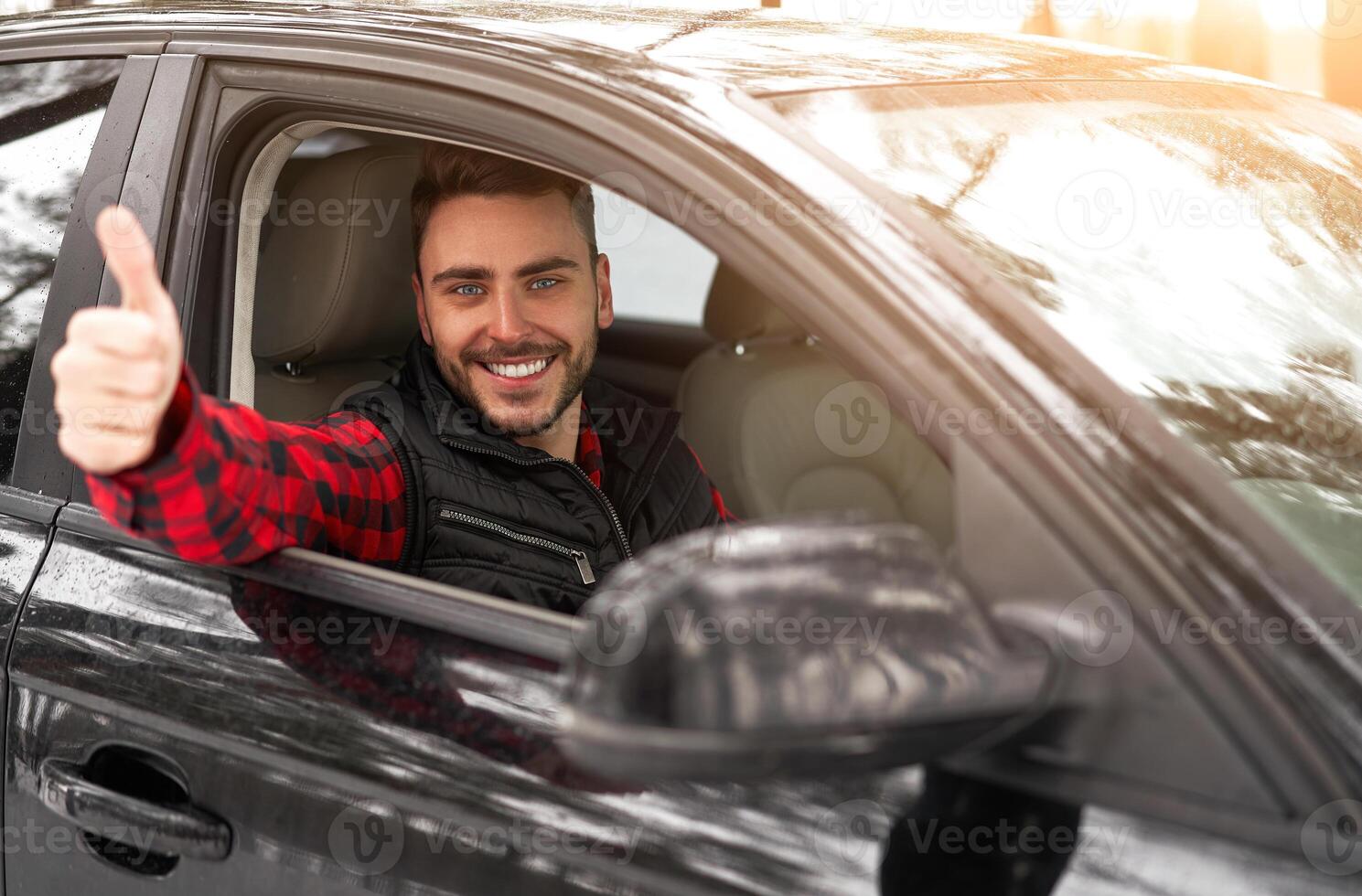 joven atractivo caucásico hombre se sienta a el rueda de su coche soleado invierno día. foto